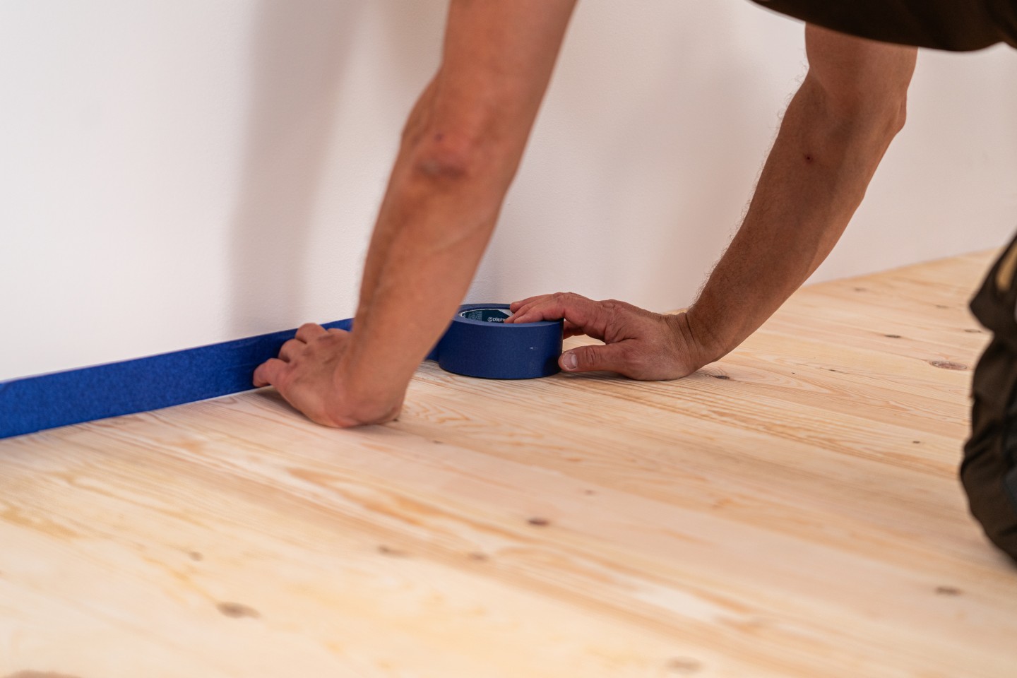 Zabezpieczenie ścian taśmą ochronną przed lakierowaniem podłogi.
