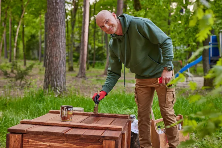 Dominik Strzelec konserwuje skrzynię ogrodową