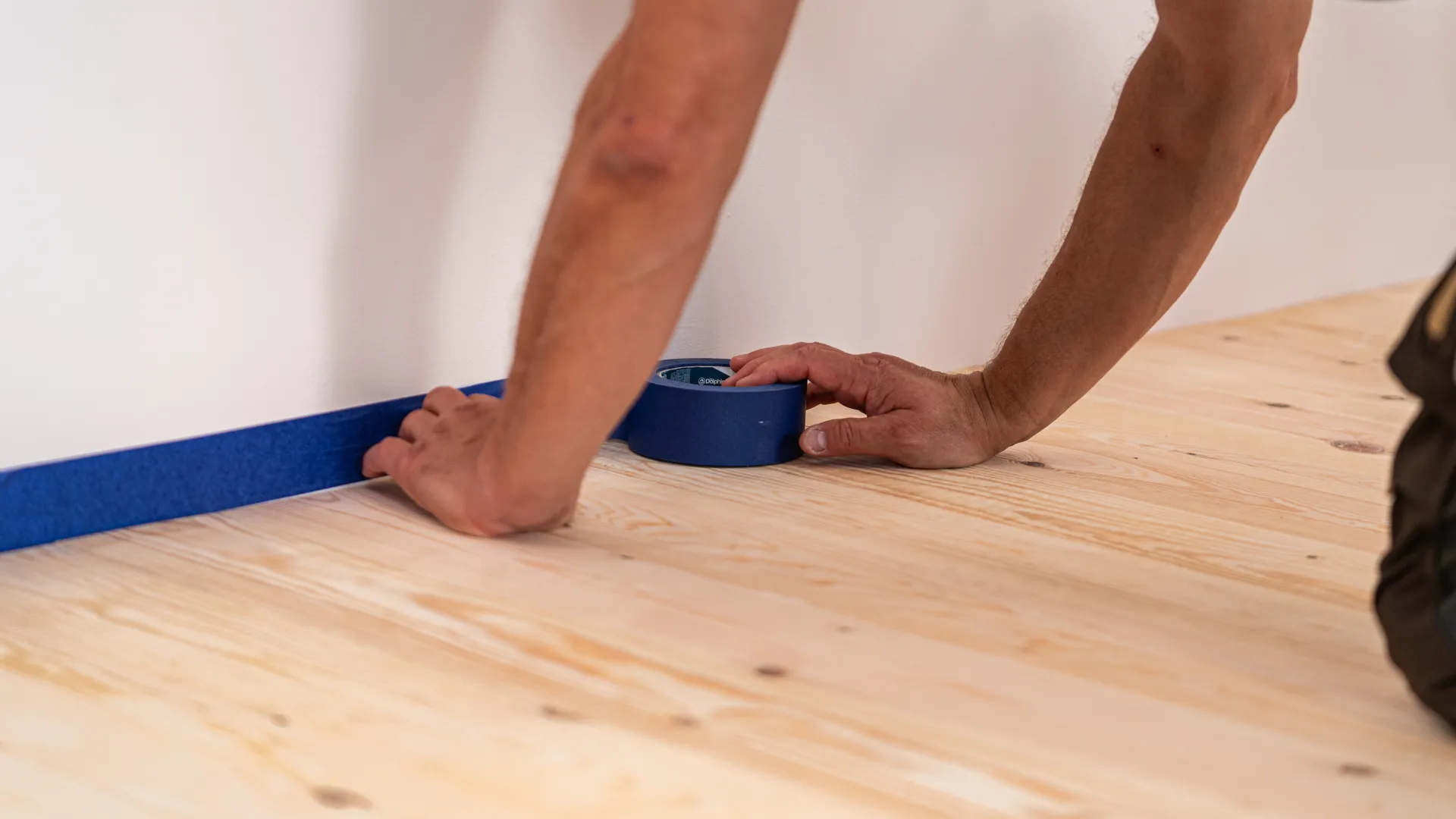 Zabezpieczenie ścian taśmą ochronną przed lakierowaniem podłogi.